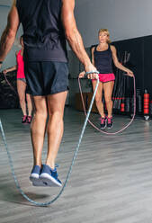 Back view of unrecognizable trainer teaching exercises with jumping ropes to women in a fitness class - ADSF50258