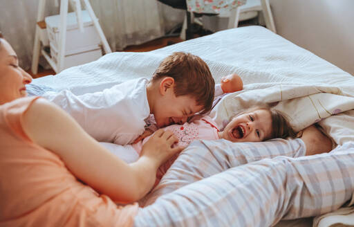 Closeup of happy family playing over the bed in a relaxed morning. Weekend family leisure time concept. - ADSF50265