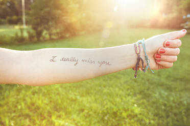 Closeup of female arm with the text -I really miss you- written in the skin over a sunny nature background - ADSF50277