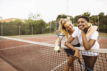 Porträt von zwei jungen schönen Frauen mit Tenniskleidung und Schlägern auf einem Tennisplatz, die bereit sind, ein Spiel zu spielen. - ADSF50299