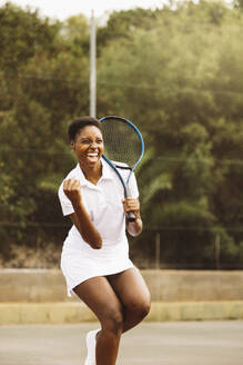 Überschwänglicher Ausdruck einer jungen schönen Frau, die einen Punkt beim Tennisspiel feiert. Glückliche Frau beim Tennisspiel mit Freunden. - ADSF50303