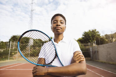 Porträt einer jungen, schönen Frau mit Tenniskleidung und Tennisschläger auf einem Tennisplatz, die bereit ist, ein Spiel zu spielen. - ADSF50307