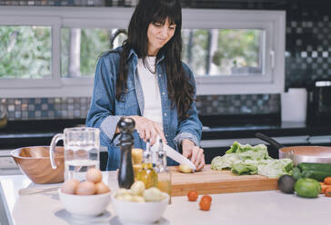 Smiling mid-adult woman preparing delicious food at home - ADSF50335