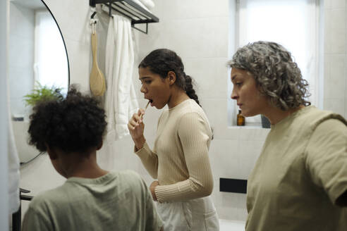 Mother looking at children brushing teeth in morning - DSHF01443