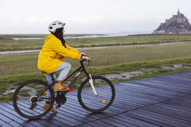 Woman cycling on boardwalk at weekend - JCCMF10968