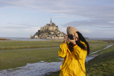 Traveler photographing with camera in front of Saint Michel castle - JCCMF10979
