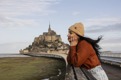 Thoughtful woman standing on bridge by Saint Michel castle - JCCMF10984