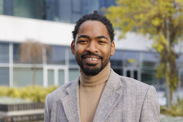 Smiling businessman with beard at office park - IKF01473