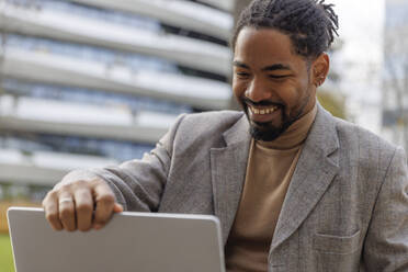 Smiling businessman talking on video call through laptop - IKF01492