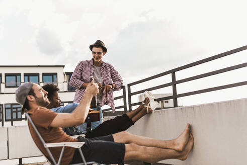 Friends having party with beer on rooftop under sky - UUF30743