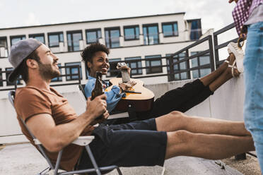 Smiling friends having party on rooftop - UUF30746