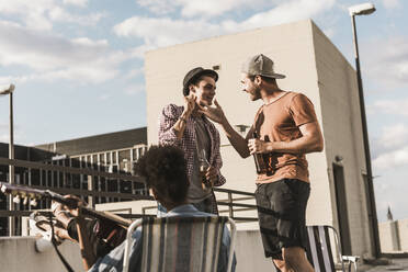 Smiling friends celebrating on terrace under sky - UUF30750