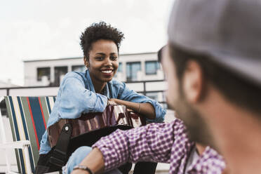 Smiling woman talking to friend on terrace - UUF30754