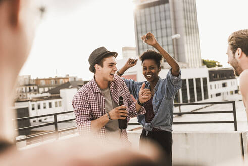 Smiling friends dancing and enjoying on rooftop - UUF30763