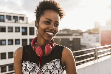 Smiling woman with headphones on rooftop - UUF30773