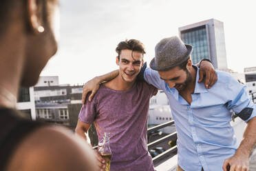 Smiling friends enjoying and spending leisure time on rooftop - UUF30777