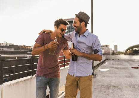 Smiling men having beer and enjoying on rooftop - UUF30783