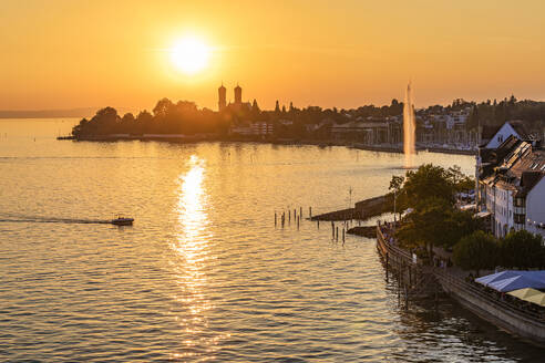 Deutschland, Baden-Württemberg, Friedrichshafen, Motorboot fährt bei Sonnenuntergang in Richtung eines kleinen Hafens - WDF07486