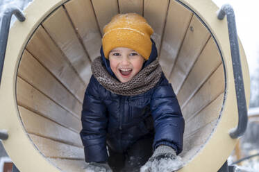 Smiling boy playing in tunnel at winter park - ANAF02543