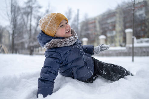 Happy boy enjoying in snow in park - ANAF02549