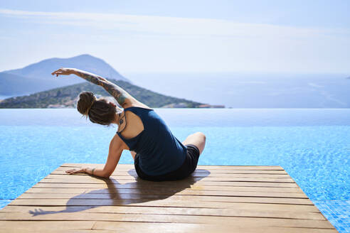 Woman doing stretching exercise near swimming pool - ANNF00801