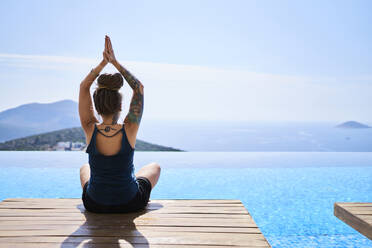 Woman practicing yoga near swimming pool - ANNF00802