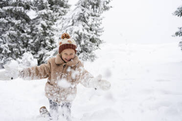 Smiling girl having fun with snow in winter forest - SVKF01783