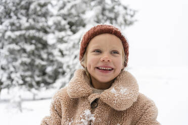 Happy girl wearing knit hat in winter forest - SVKF01785