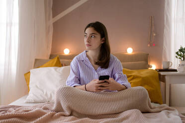 Young teenage girl srolling her smartphone in a room. - HPIF35284