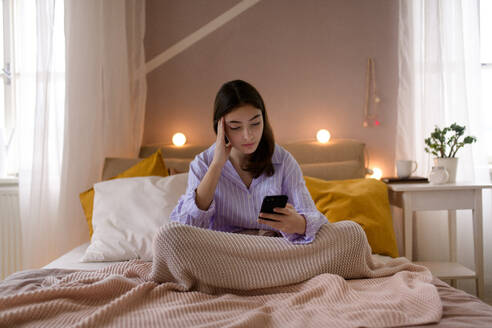 Junges Mädchen im Teenageralter rollt ihr Smartphone in einem Zimmer. - HPIF35285