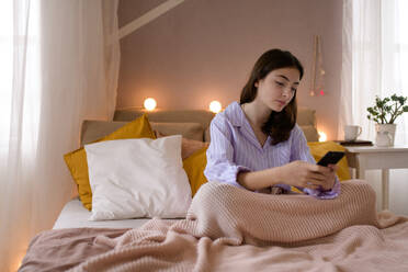 Young teenage girl srolling her smartphone in a room. - HPIF35286