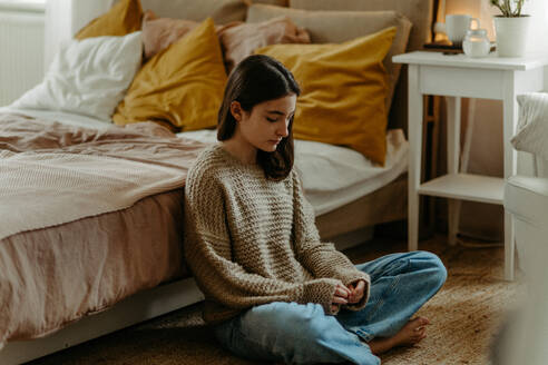 Unglückliches Teenager-Mädchen, das in ihrem Zimmer auf dem Boden sitzt, Konzept der psychischen Gesundheit. - HPIF35290