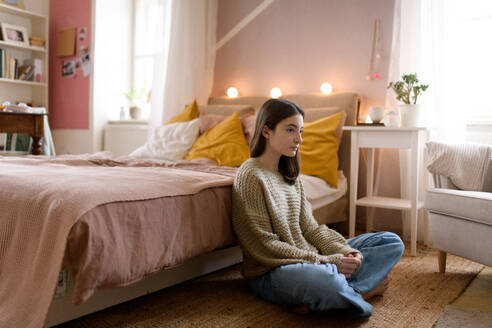 Unglückliches Teenager-Mädchen, das in ihrem Zimmer auf dem Boden sitzt, Konzept der psychischen Gesundheit. - HPIF35291