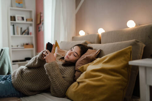 Junges Mädchen im Teenageralter rollt ihr Smartphone in einem Zimmer. - HPIF35305