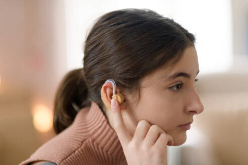 Porträt eines Mädchens im Teenageralter mit Hörgerät im Zimmer. - HPIF35322