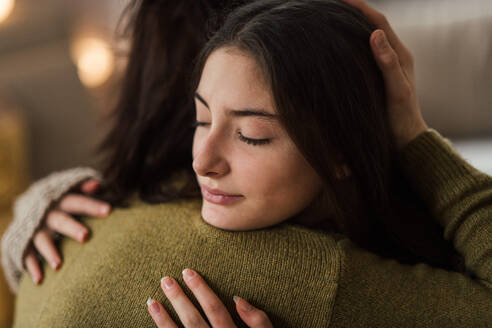 Junges Mädchen im Teenageralter umarmt ihre Mutter zu Hause. - HPIF35323