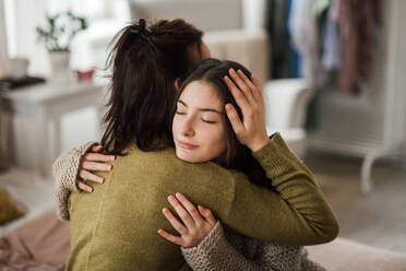 Young teenage girl hugging her mother at home. - HPIF35324