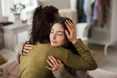 Junges Mädchen im Teenageralter umarmt ihre Mutter zu Hause. - HPIF35324
