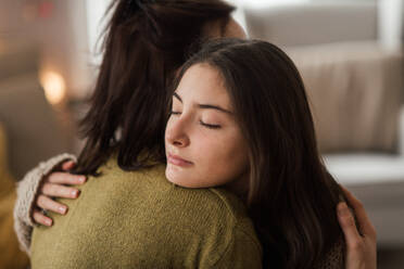 Young teenage girl hugging her mother at home. - HPIF35325