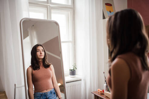 Junges Mädchen im Teenageralter schaut in den Spiegel im Zimmer. - HPIF35341