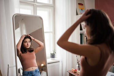 Young teenage girl looking in the mirror in the room. - HPIF35342