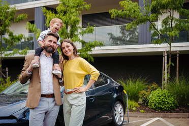 Glückliche junge Familie mit kleinem Sohn, der auf das Aufladen des Elektroautos wartet. - HPIF35369