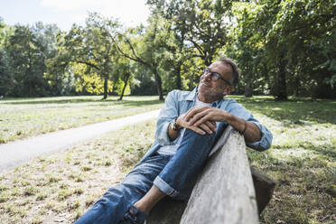 Thoughtful senior man sitting on bench in park - UUF30805