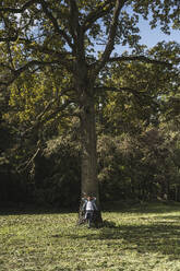 Senior man standing in front of tree at park - UUF30807