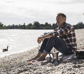 Thoughtful senior man spending leisure time by sea at beach - UUF30846