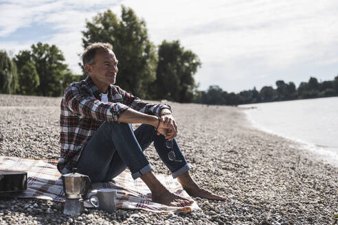 Contemplative senior man spending leisure time at beach - UUF30847