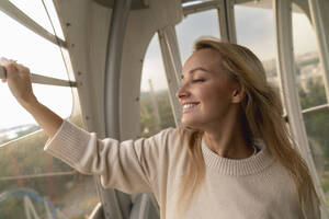 Happy blond woman enjoying in Ferris wheel - VPIF08974