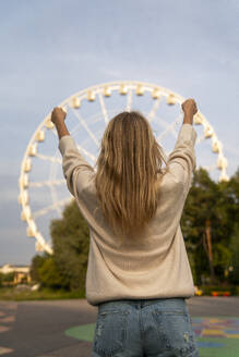 Woman pretending to hold Ferris wheel at amusement park - VPIF08981