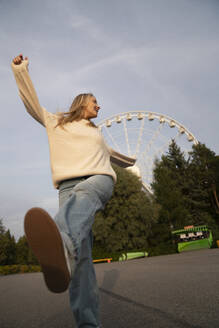 Happy woman enjoying in amusement park at sunset - VPIF08982