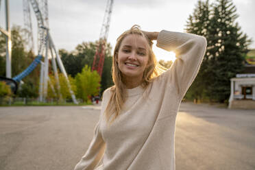 Happy young woman in amusement park at sunset - VPIF08985